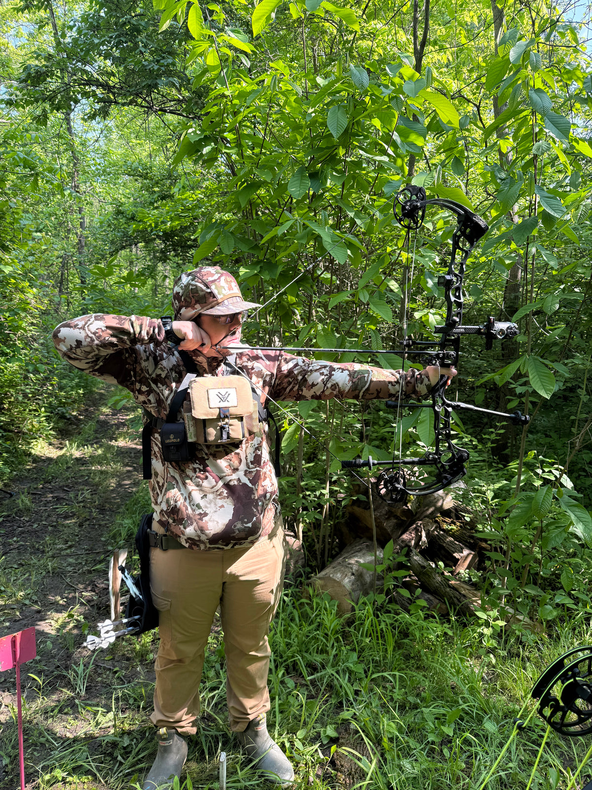 Archer at full draw in summer woods